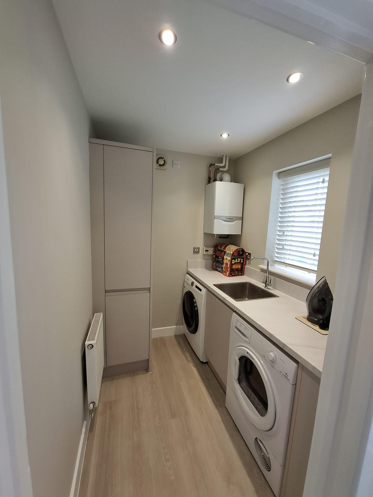 A modern utility room with light-coloured walls and floor