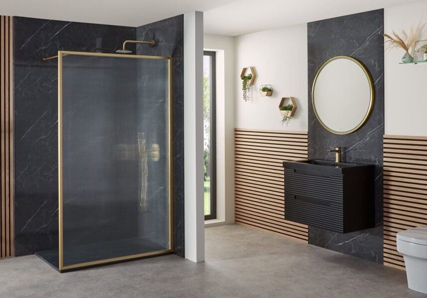 Modern bathroom with fluting Modern bathroom with black and wood panelled walls, gold-framed glass shower, round mirror, black vanity unit, wall-mounted toilet, towel rail, and shelves with decor and toiletries. Large window provides natural light.